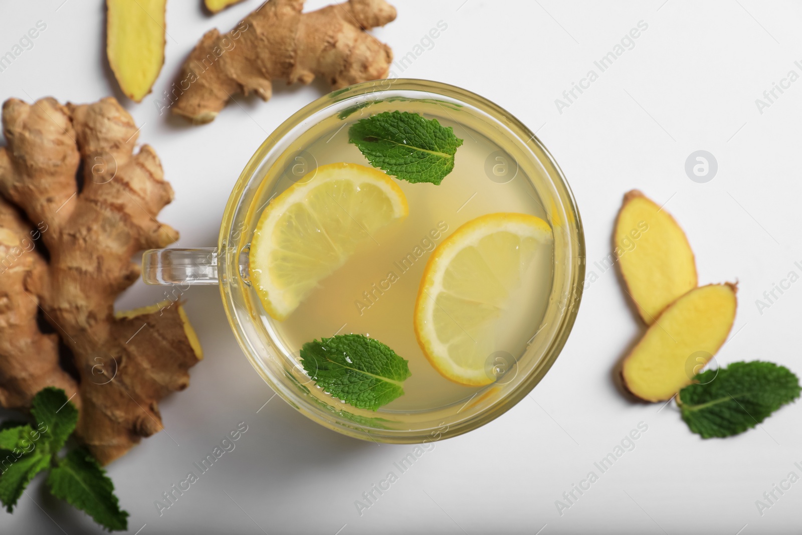 Photo of Delicious ginger tea, lemon and mint on light grey background, flat lay