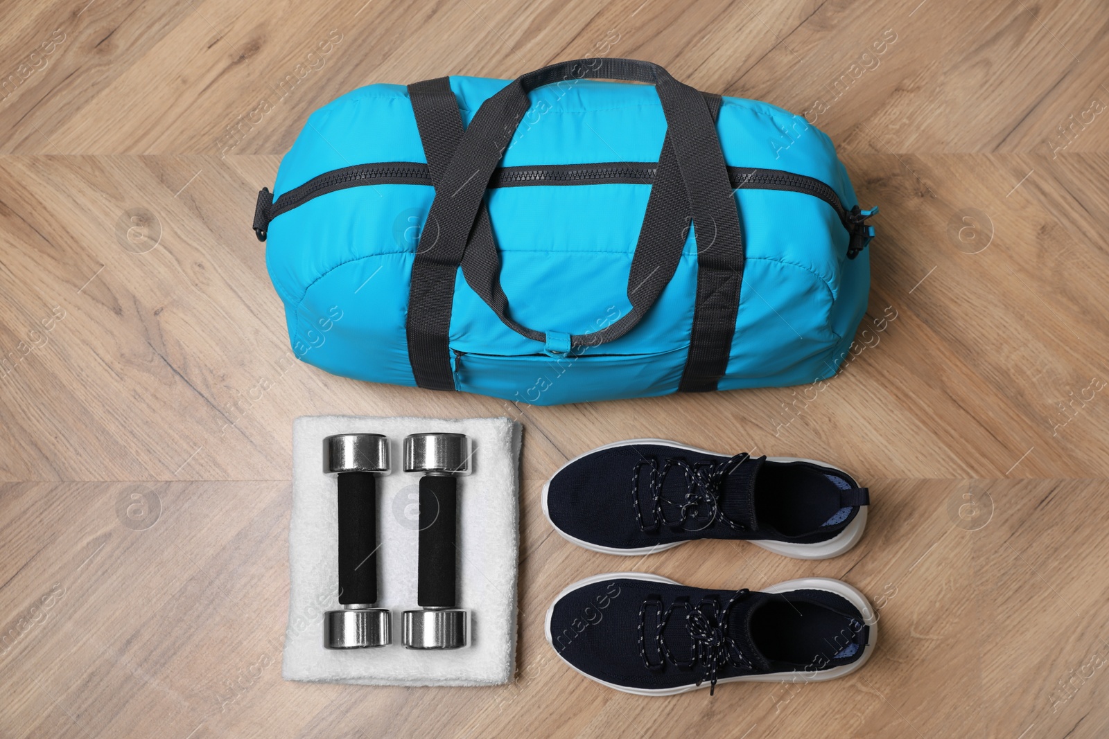 Photo of Blue gym bag and sports accessories on wooden floor, flat lay