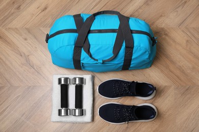 Photo of Blue gym bag and sports accessories on wooden floor, flat lay