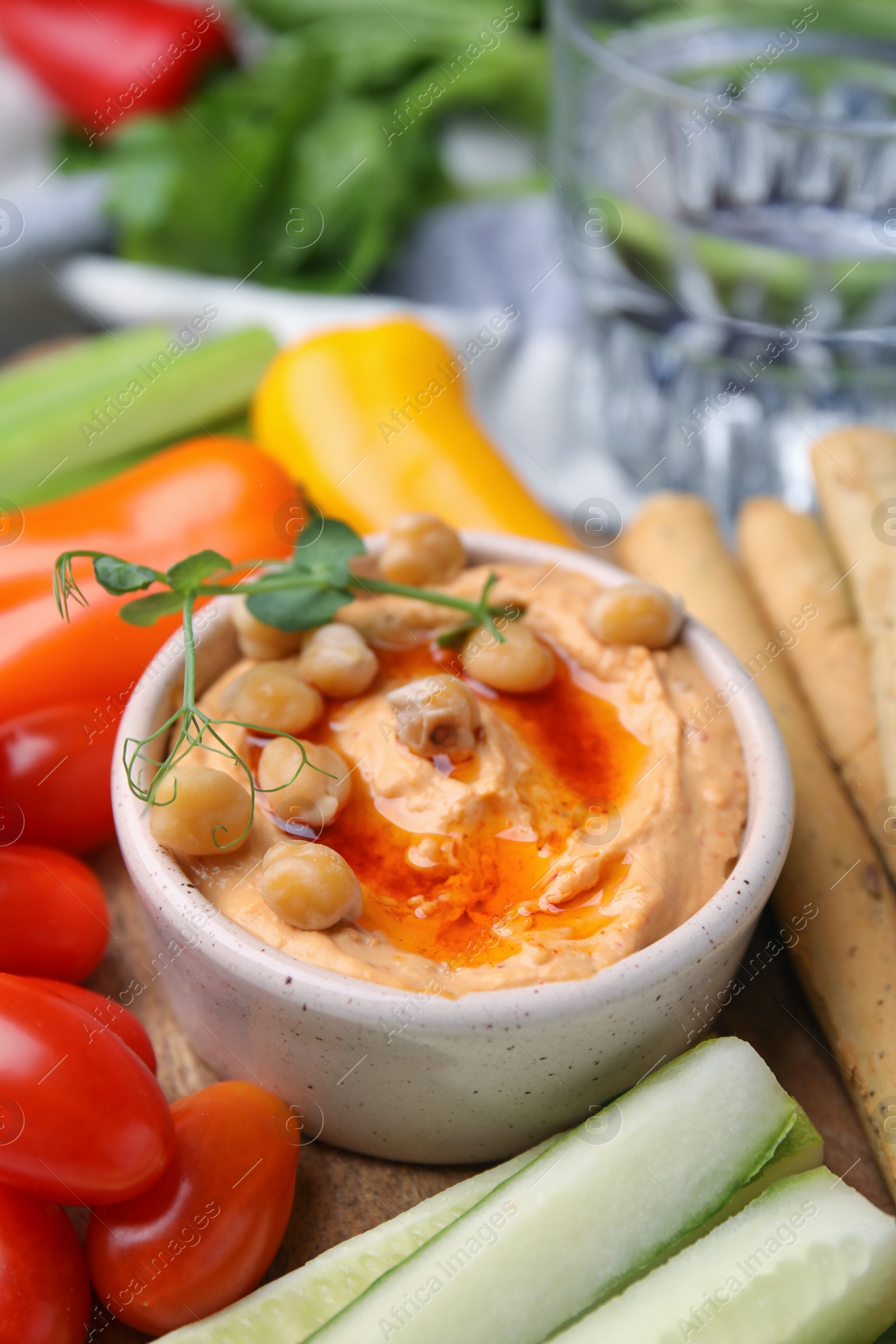 Photo of Board with delicious hummus, grissini sticks and fresh vegetables, closeup