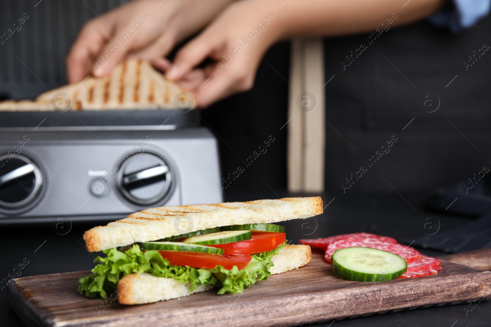 Photo of Tasty sandwich with tomato and cucumber on black table, closeup