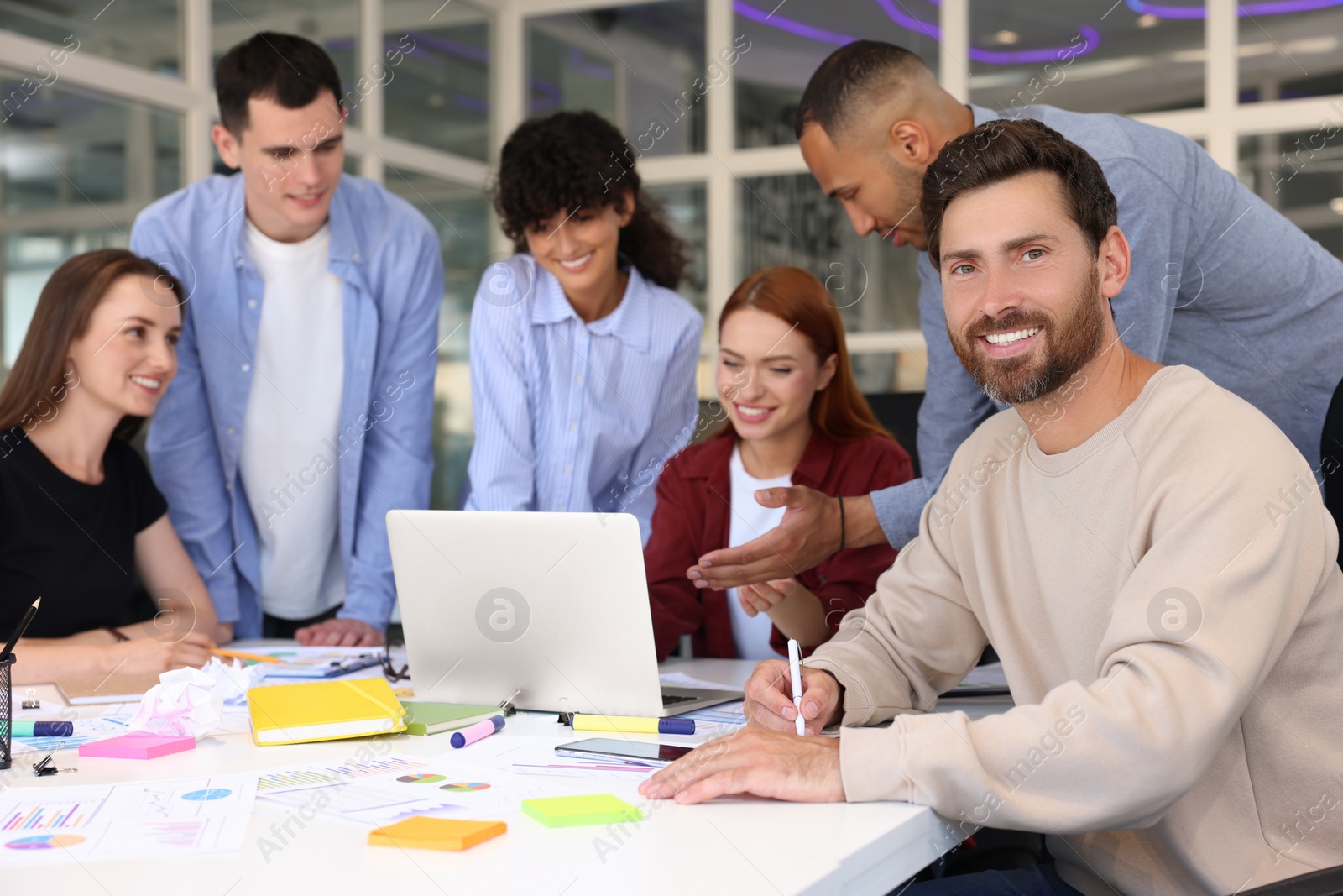 Photo of Team of employees working together at table in office. Startup project