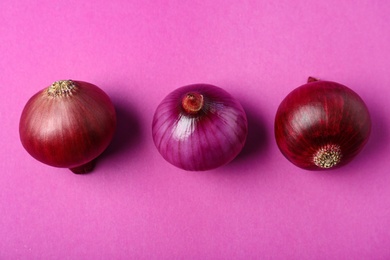 Photo of Whole red onion bulbs on pink background, flat lay