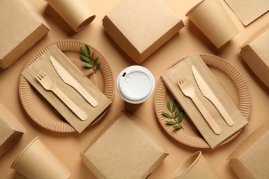 Photo of Paper and wooden tableware with green twigs on beige background, flat lay. Eco friendly lifestyle