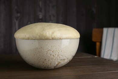 Bowl of fresh yeast dough on wooden table