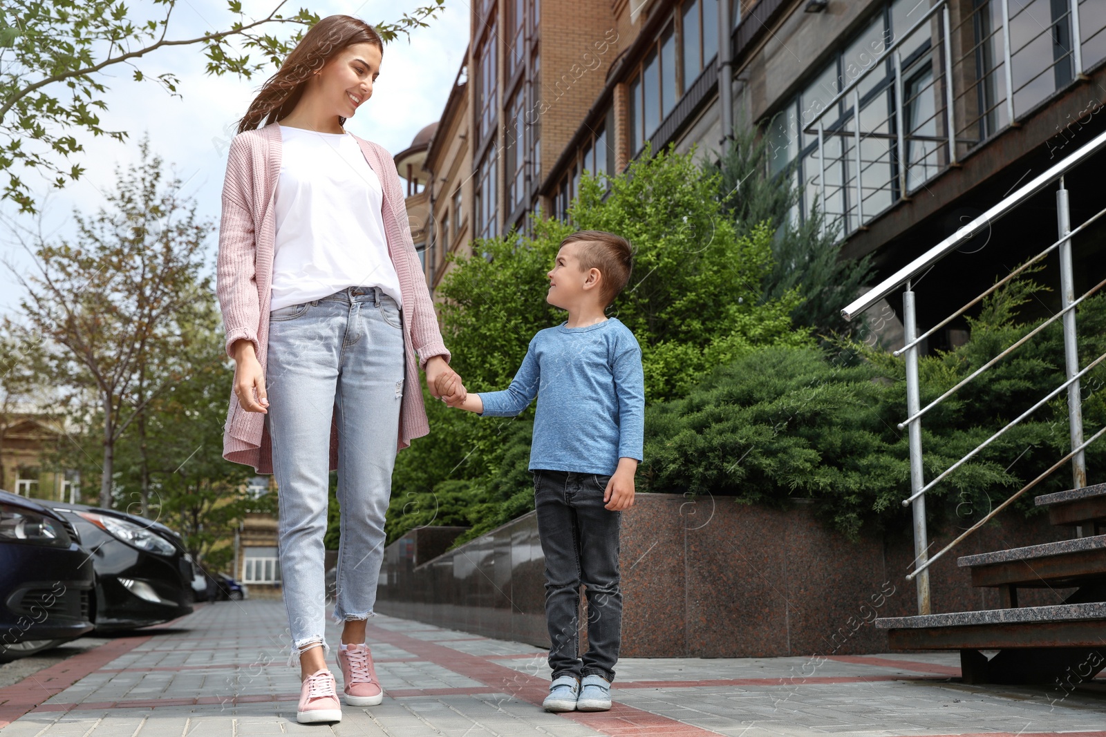 Photo of Happy child and mother holding hands outdoors, low angle view. Family weekend