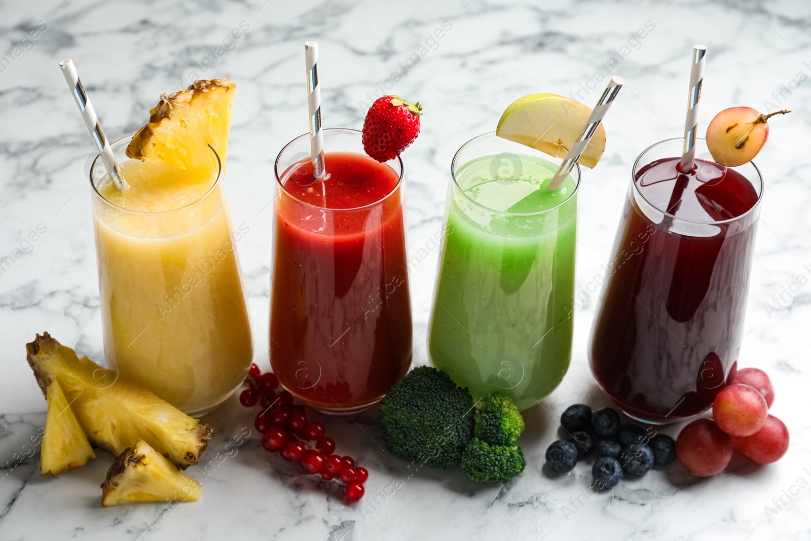 Photo of Glasses of delicious juices and fresh ingredients on white marble table