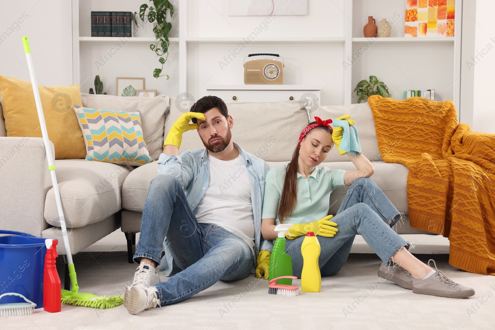 Photo of Spring cleaning. Tired couple with detergents and mop in living room