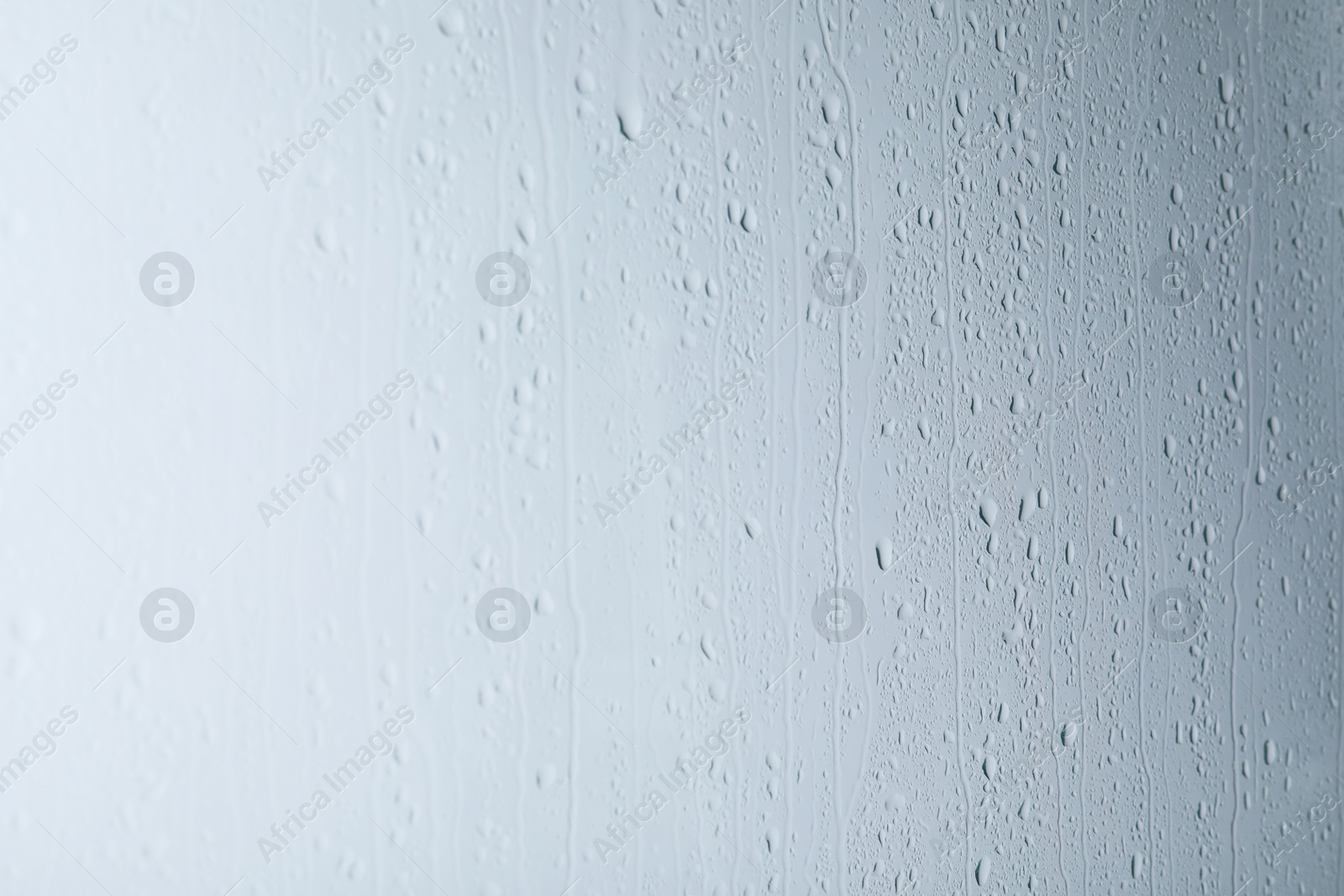 Photo of Glass with rain drops on light background