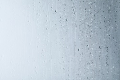 Photo of Glass with rain drops on light background