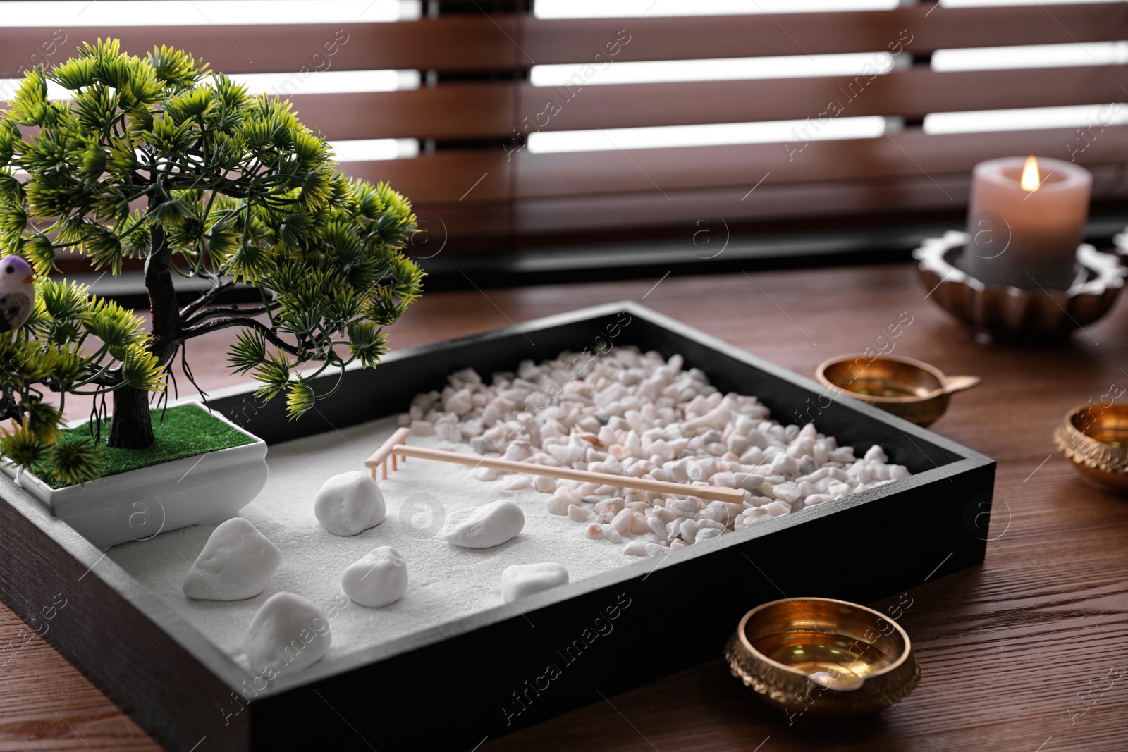 Photo of Beautiful miniature zen garden, candles and oil lamps on wooden table