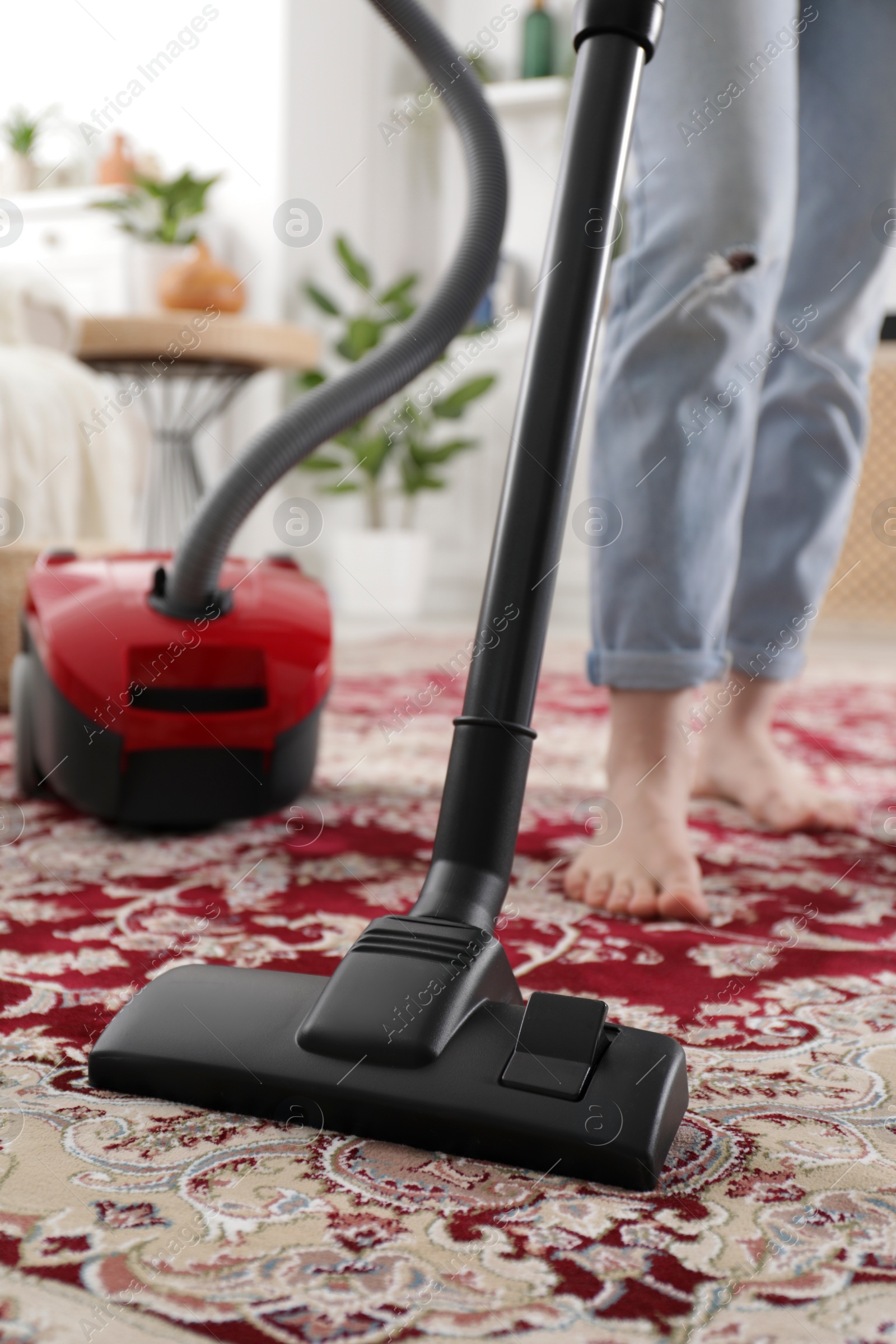 Photo of Woman cleaning carpet with vacuum cleaner at home, closeup