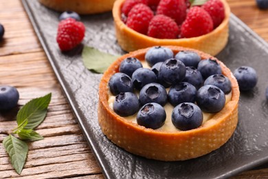 Photo of Tartlet with fresh blueberries on wooden table, closeup. Delicious dessert