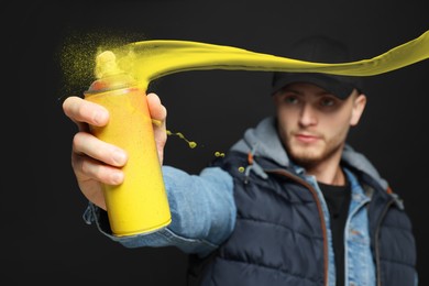 Image of Handsome man spraying yellow paint against black background