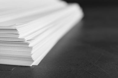 Photo of Stack of blank paper on grey stone table, closeup. Space for text