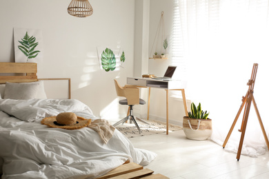 Photo of Stylish room interior with workplace and bed