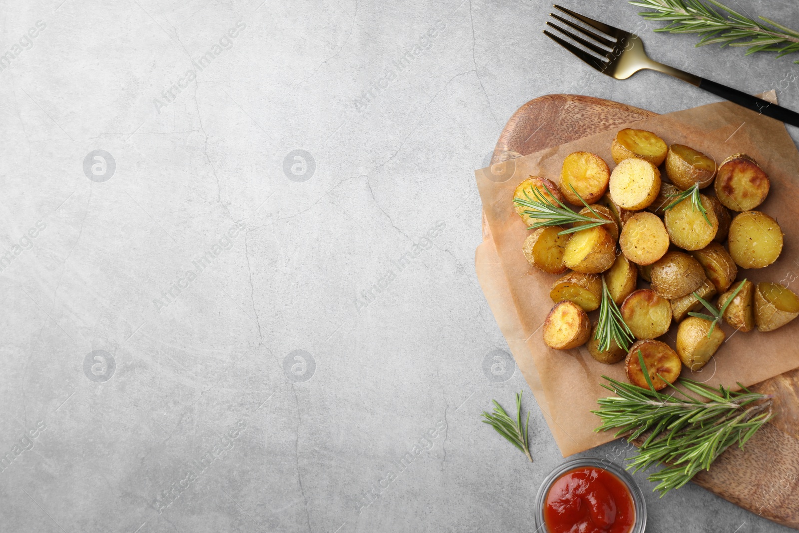 Photo of Tasty baked potato with aromatic rosemary and sauce served on grey textured table, flat lay. Space for text