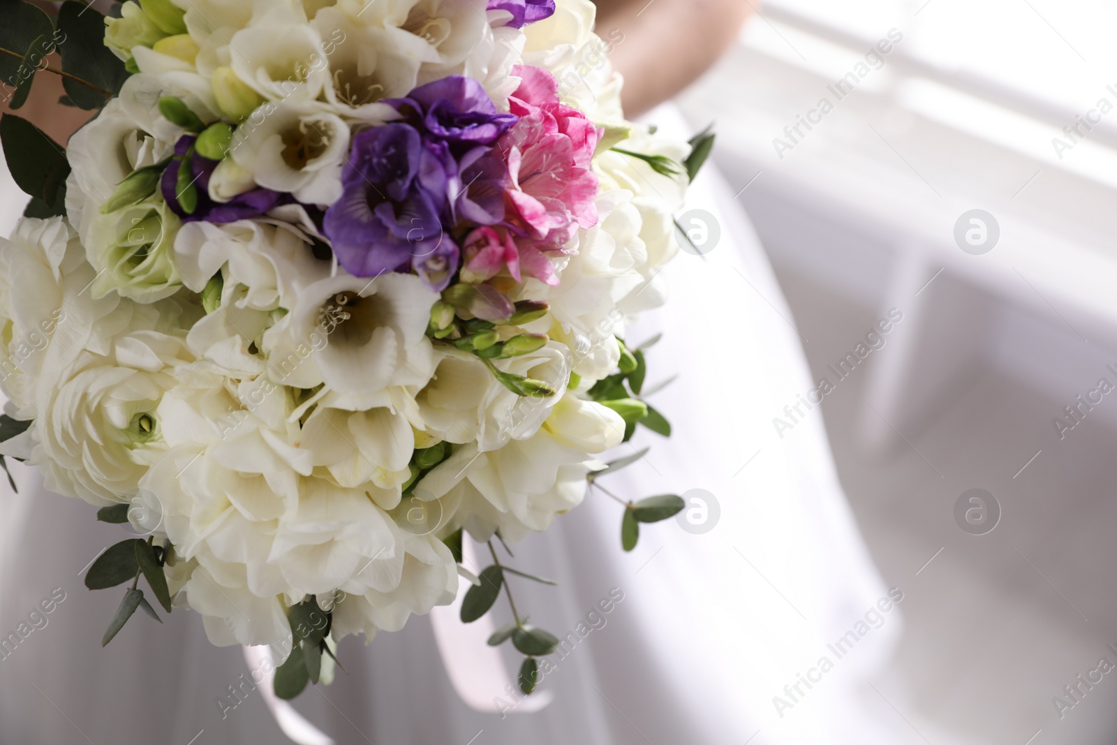 Photo of Bride holding beautiful bouquet with spring freesia flowers, closeup