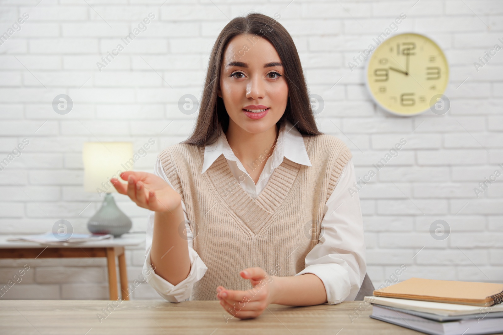 Photo of Young businesswoman conducting webinar at desk in room