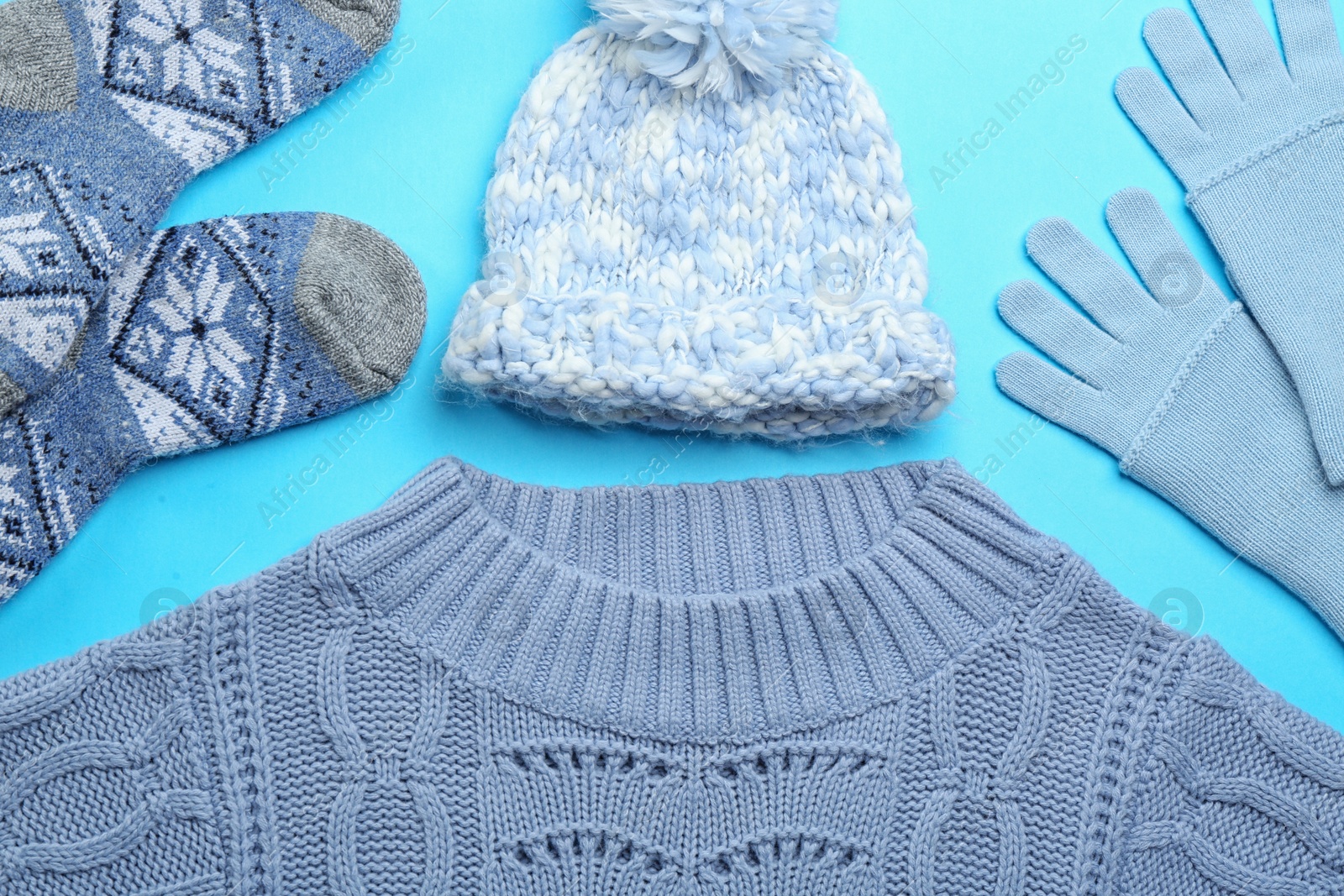 Photo of Flat lay composition with warm clothes on light blue background