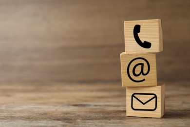 Image of Hotline service. Cubes with icons on wooden background, space for text