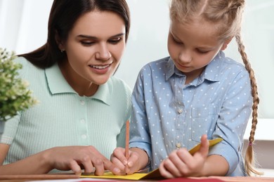 Cute little girl with her mother making beautiful greeting card at home
