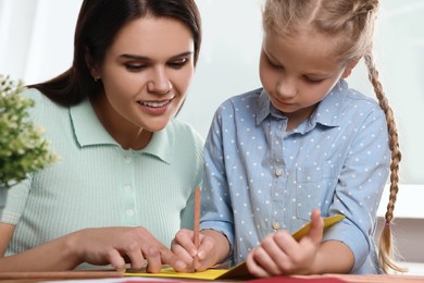 Photo of Cute little girl with her mother making beautiful greeting card at home