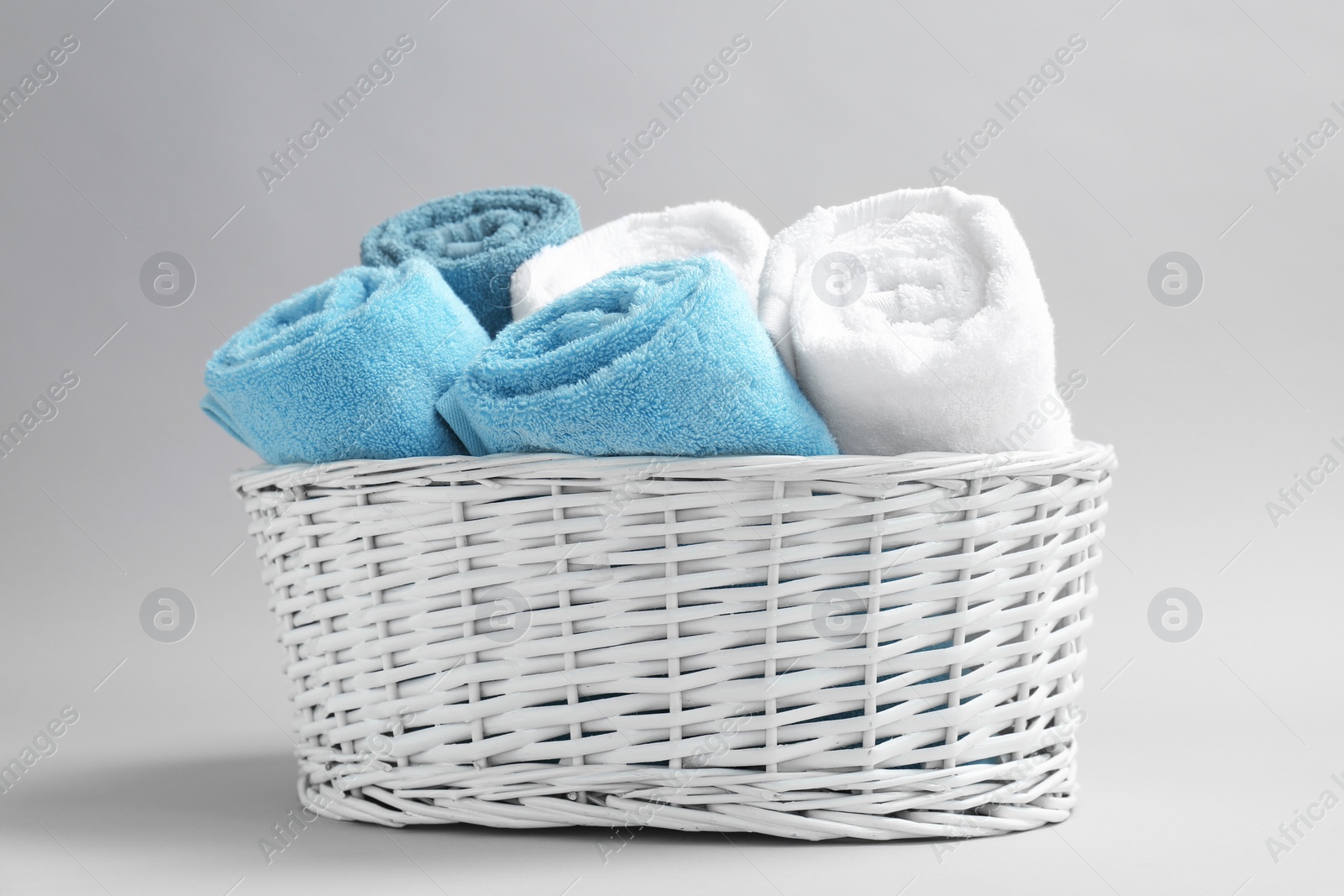 Photo of Basket with soft bath towels on grey background