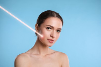 Laser mole removal. Woman with ray pointed at her skin during procedure on light blue background. Space for text