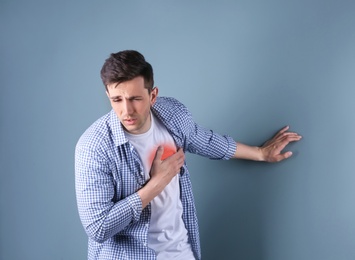 Photo of Young man having heart attack on color background