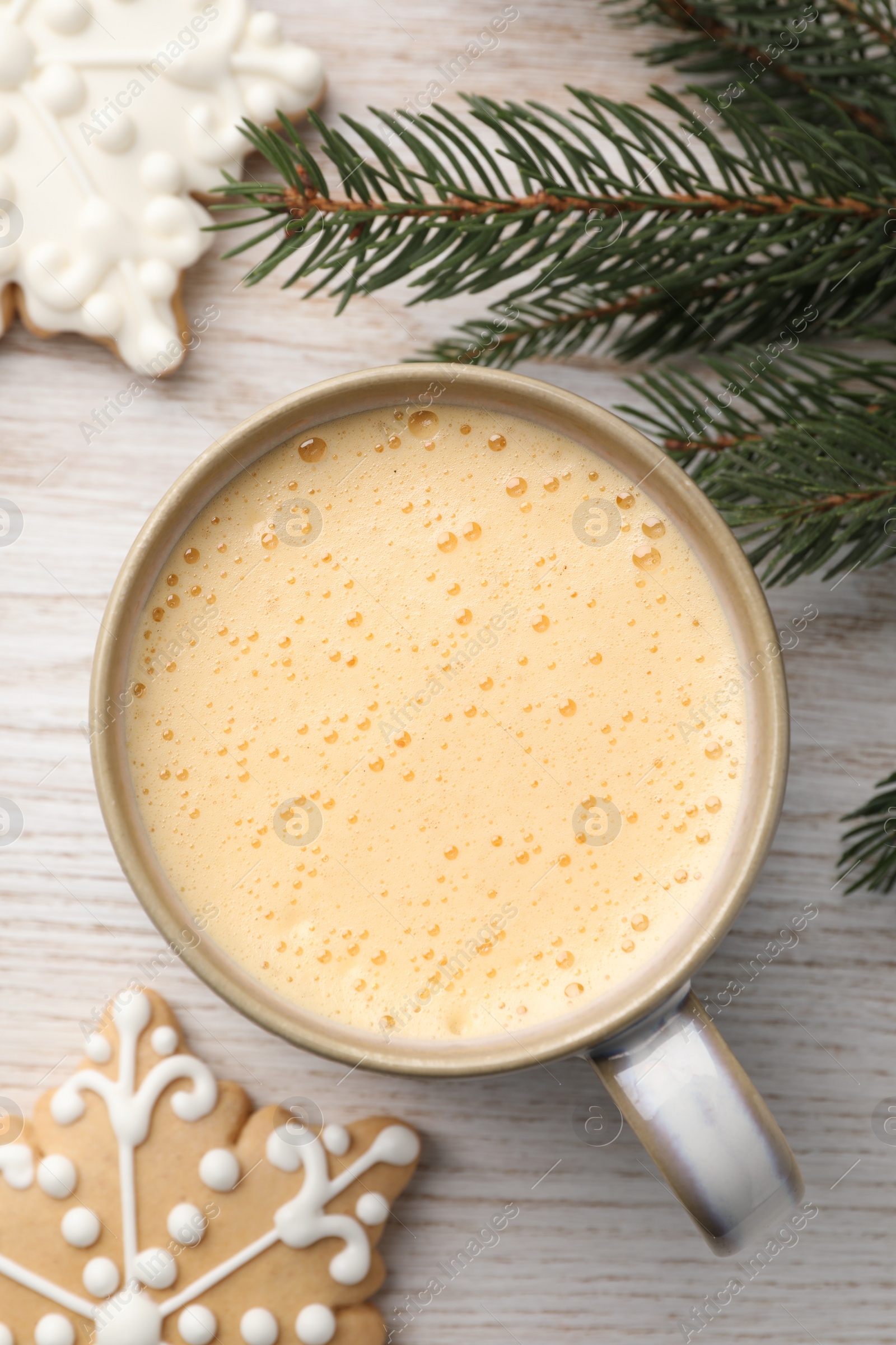 Photo of Cup of delicious eggnog, fir branch and cookies on wooden table, flat lay