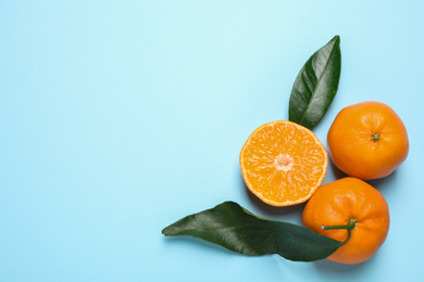 Flat lay composition with fresh ripe tangerines and leaves on light blue background, space for text. Citrus fruit