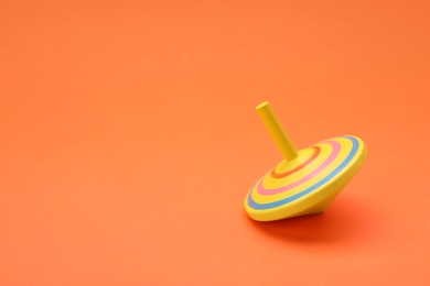 One bright spinning top on orange background, space for text. Toy whirligig