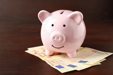 Ceramic piggy bank and banknotes on wooden table