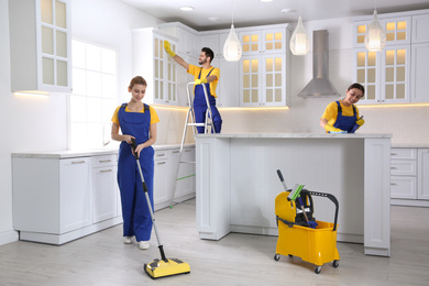 Photo of Team of professional janitors cleaning modern kitchen