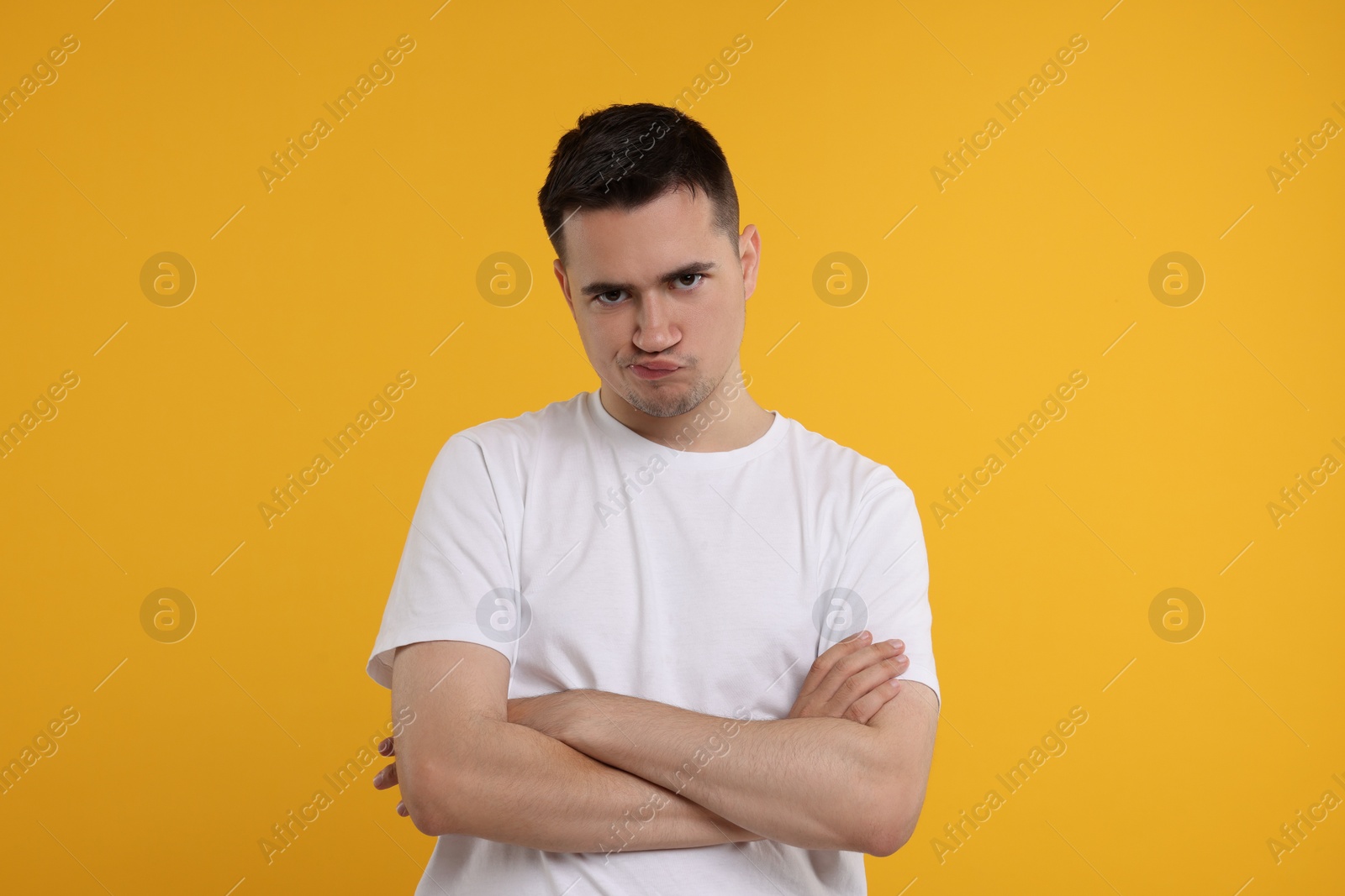 Photo of Resentful man with crossed arms on orange background