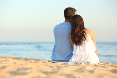 Happy young couple sitting together on beach