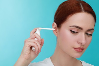 Photo of Woman using ear spray on light blue background