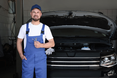 Professional auto mechanic near modern car in service center