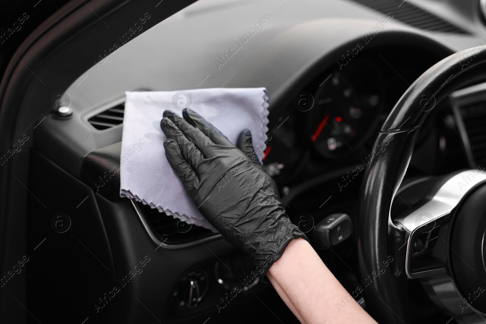 Photo of Woman wiping her modern car with rag, closeup