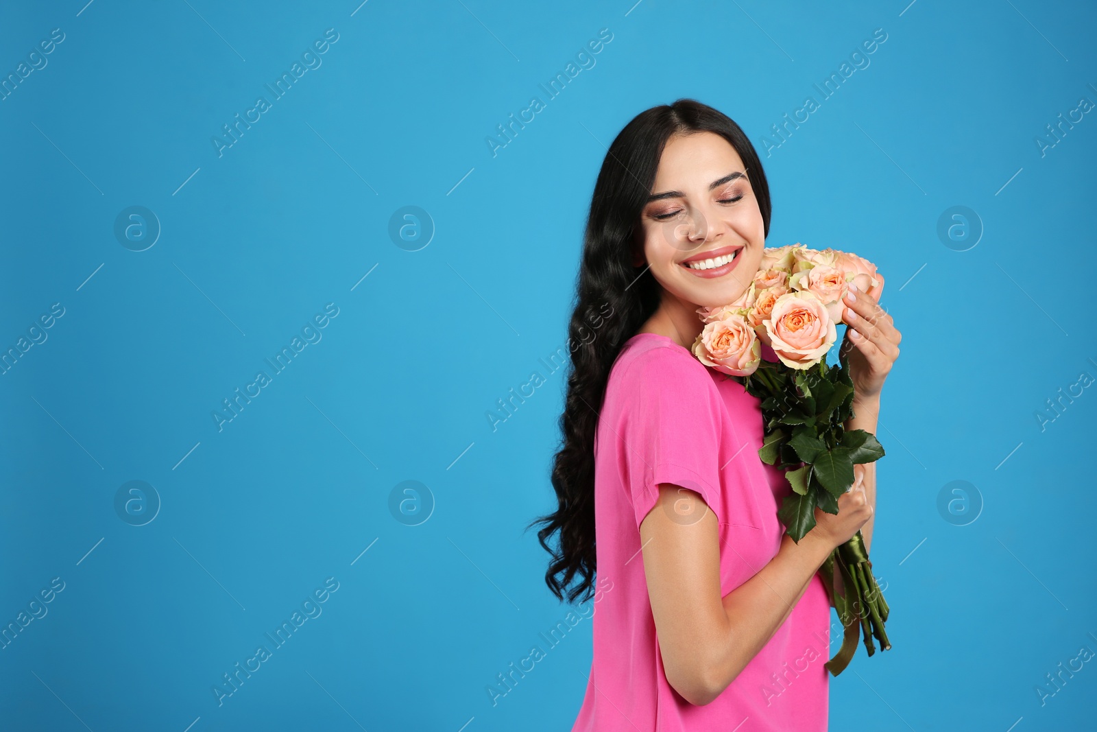 Photo of Portrait of smiling woman with beautiful bouquet on light blue background. Space for text
