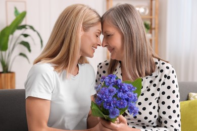 Photo of Happy mature mother and her daughter with beautiful cornflowers at home