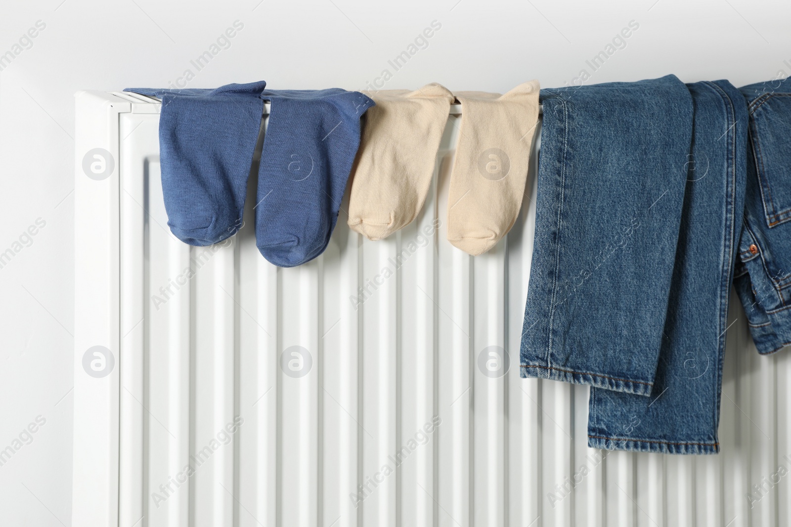 Photo of Jeans and socks on heating radiator near white wall