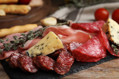 Photo of Tasty ham with other delicacies served on wooden table, closeup