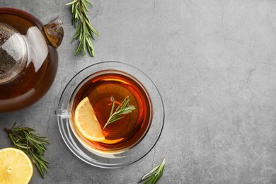 Aromatic herbal tea with rosemary and lemon on grey table, flat lay. Space for text