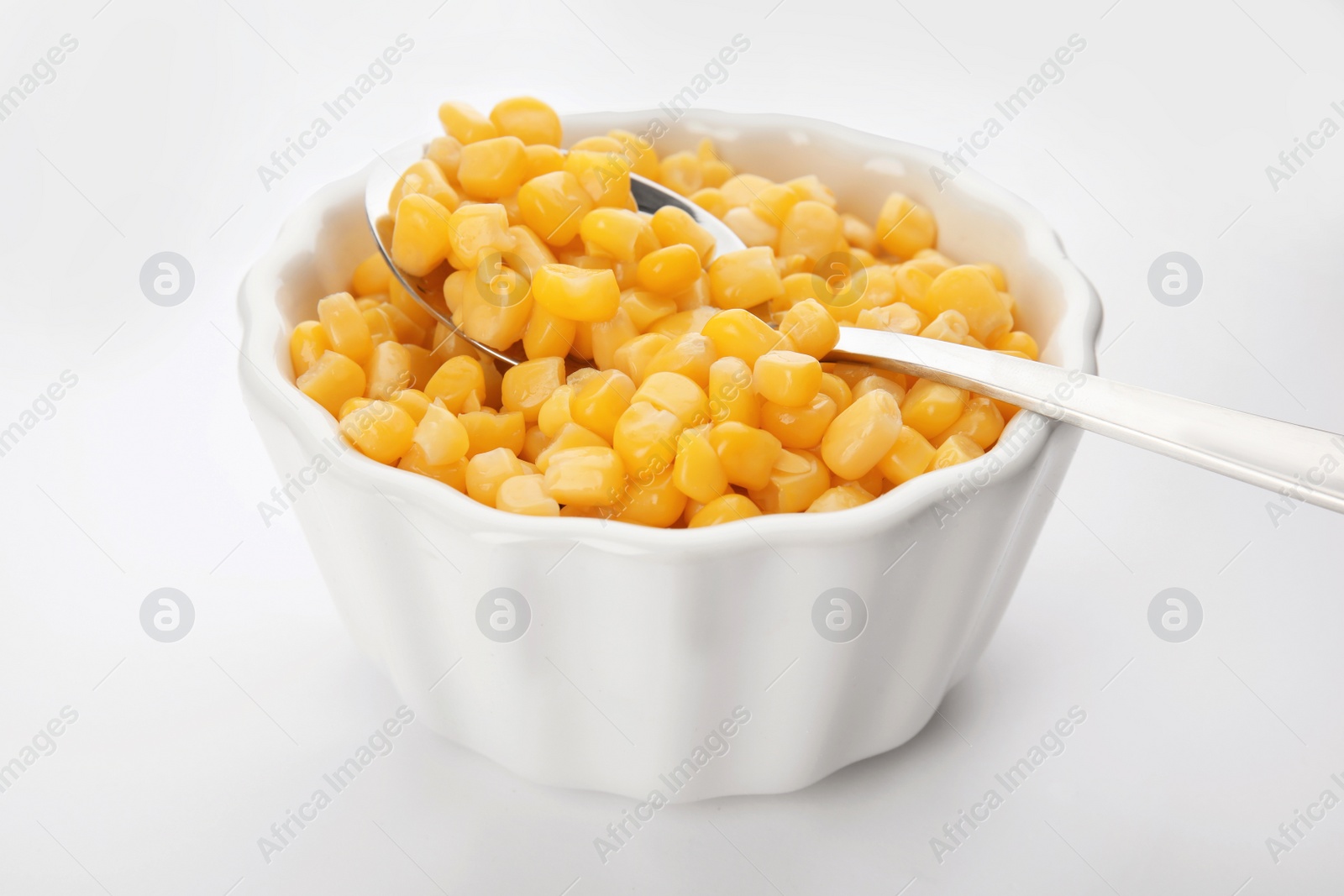 Photo of Bowl and spoon with corn kernels on white background