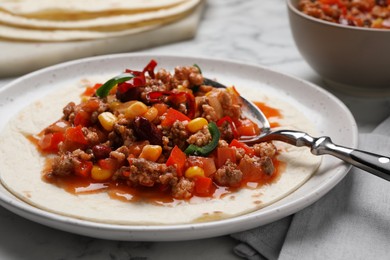Photo of Tasty chili con carne with tortilla on white table, closeup