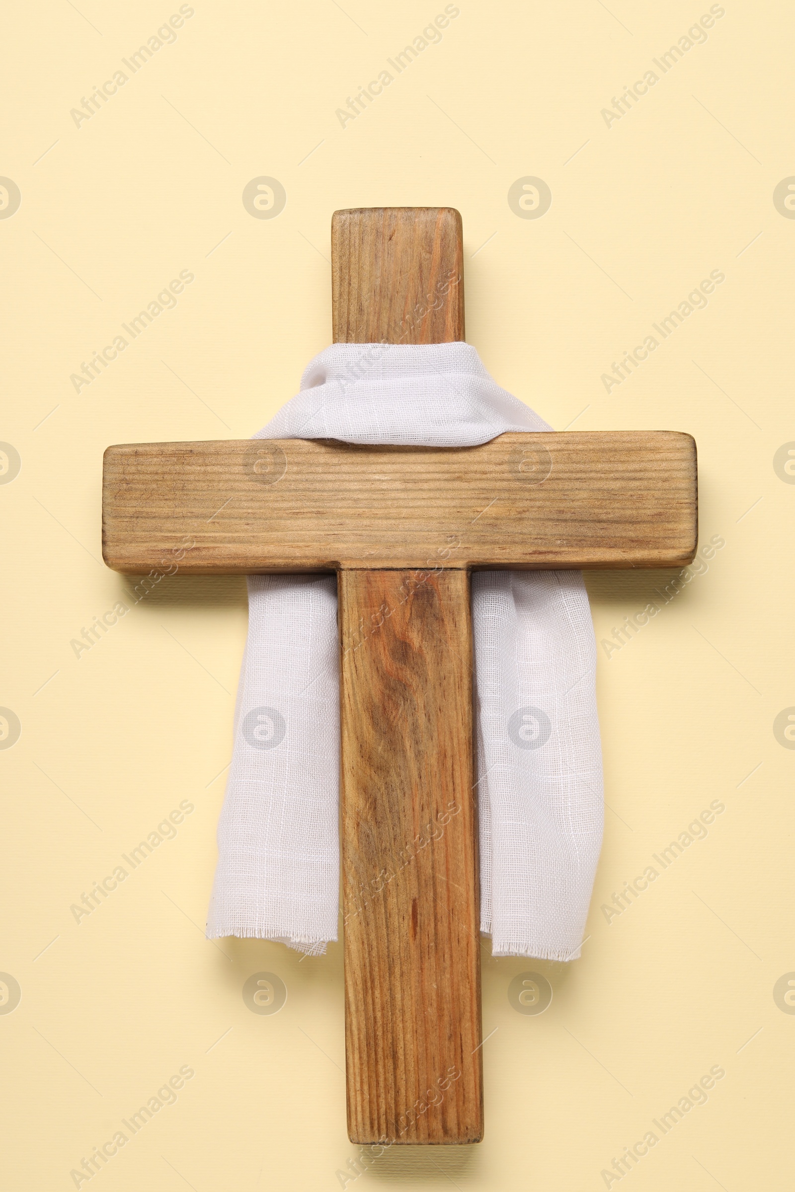 Photo of Wooden cross and white cloth on beige background, top view. Easter attributes