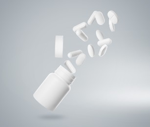 Image of Many different white pills falling into bottle on light grey background