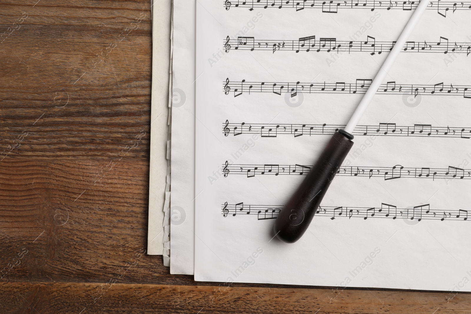 Photo of Conductor's baton and sheet music on wooden table, flat lay